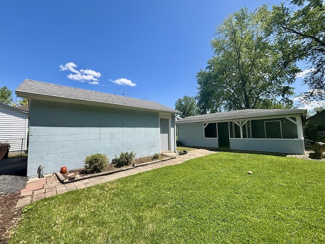 418 Starr St, Belvidere, IL 61008 - back of house with a lawn, concrete block siding, and a sunroom