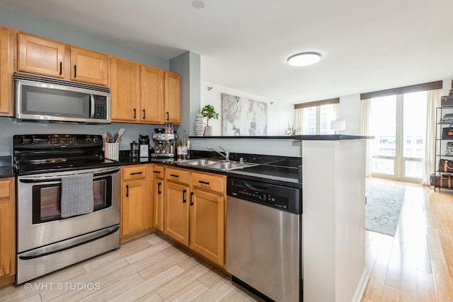 345 N Lasalle Dr Unit 802, Chicago, IL 60610 - kitchen featuring appliances with stainless steel finishes, light wood finished floors, dark countertops, a peninsula, and a sink