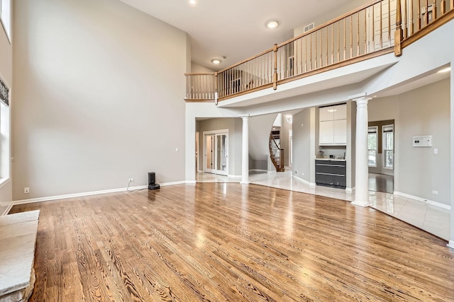 830 W Lukas Ave, Palatine, IL 60067 - unfurnished living room featuring decorative columns, light wood finished floors, a towering ceiling, recessed lighting, and baseboards