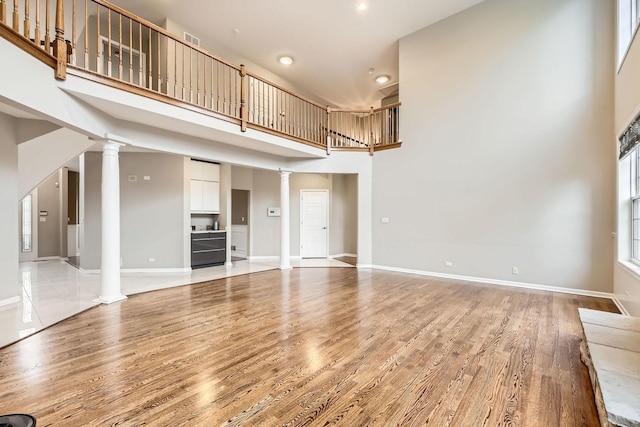 830 W Lukas Ave, Palatine, IL 60067 - unfurnished living room with ornate columns, a towering ceiling, light wood finished floors, recessed lighting, and baseboards