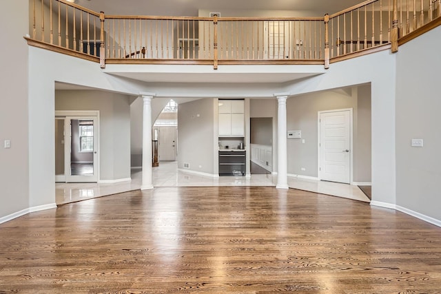 830 W Lukas Ave, Palatine, IL 60067 - unfurnished living room with ornate columns, a high ceiling, wood finished floors, and baseboards