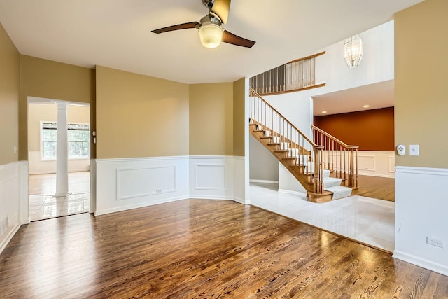 830 W Lukas Ave, Palatine, IL 60067 - unfurnished living room featuring wood finished floors, a ceiling fan, decorative columns, stairway, and a wainscoted wall