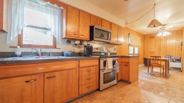 13122 S Escanaba Ave, Chicago, IL 60633 - kitchen featuring appliances with stainless steel finishes, a sink, brown cabinetry, a baseboard heating unit, and healthy amount of natural light