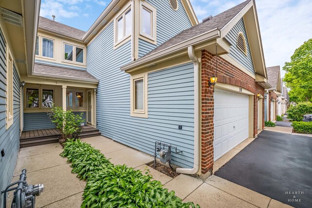 358 Bristol Ln, Fox River Grove, IL 60021 - view of side of home with a garage, a shingled roof, driveway, and brick siding