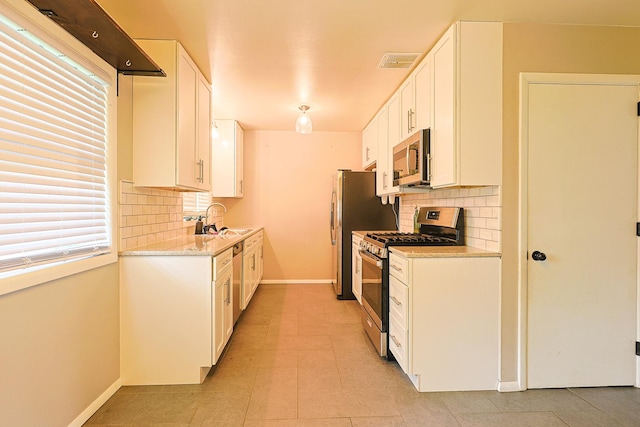 309 River Dr, Dekalb, IL 60115 - kitchen featuring stainless steel appliances, baseboards, decorative backsplash, a sink, and white cabinetry