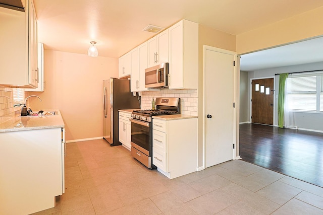 309 River Dr, Dekalb, IL 60115 - kitchen featuring stainless steel appliances, a sink, decorative backsplash, and white cabinets