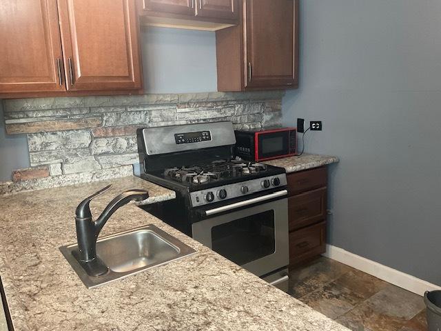7854 S S Shore Dr Unit 306, Chicago, IL 60649 - kitchen featuring stainless steel gas range oven, a sink, baseboards, light stone counters, and backsplash
