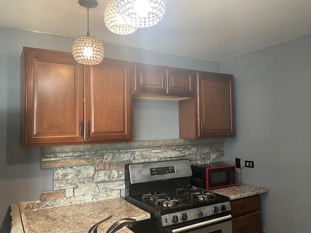 7854 S S Shore Dr Unit 306, Chicago, IL 60649 - kitchen with stainless steel gas range, black microwave, backsplash, and light countertops