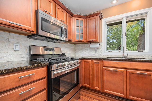 831 W Marywood Ave, Aurora, IL 60505 - kitchen with stainless steel appliances, a sink, dark stone counters, brown cabinets, and tasteful backsplash