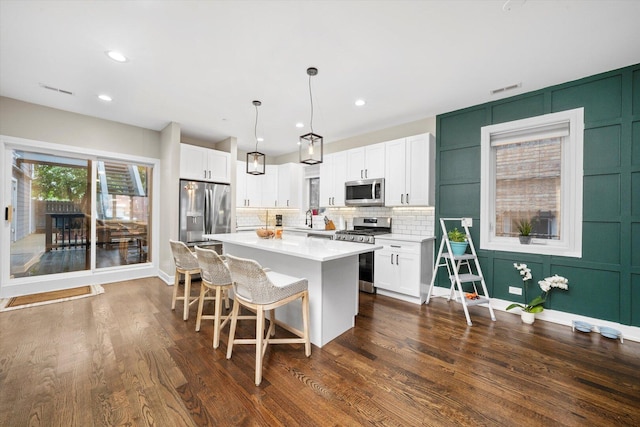 7230 W Belden Ave Unit 1, Elmwood Park, IL 60707 - kitchen with stainless steel appliances, a kitchen island, white cabinetry, light countertops, and a decorative wall
