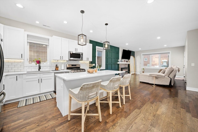 7230 W Belden Ave Unit 1, Elmwood Park, IL 60707 - kitchen featuring stainless steel appliances, a sink, open floor plan, backsplash, and a kitchen island