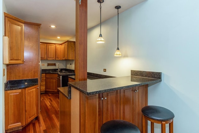 4419 S Wallace St, Chicago, IL 60609 - kitchen with a peninsula, dark wood-style floors, brown cabinets, a breakfast bar, and hanging light fixtures