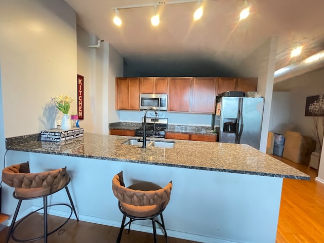 2323 W Pershing Rd Unit 421, Chicago, IL 60609 - kitchen with stainless steel appliances, a sink, a peninsula, rail lighting, and dark stone countertops