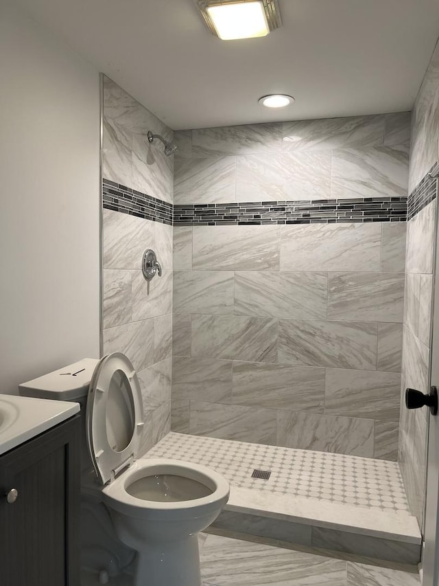 full bath featuring toilet, a tile shower, and vanity