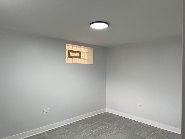 spare room with baseboards and dark marble finish floors