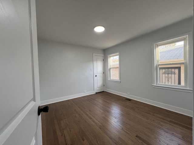 spare room featuring dark wood-style flooring and baseboards
