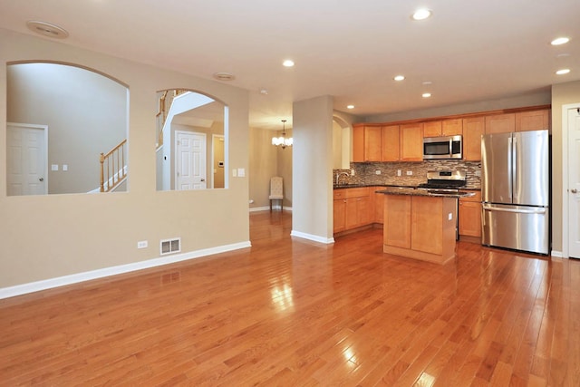 1437 Sturgeon Bay Ct, Schaumburg, IL 60173 - kitchen with appliances with stainless steel finishes, a sink, arched walkways, a center island, and light wood-style flooring