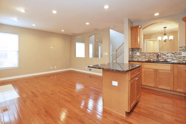 1437 Sturgeon Bay Ct, Schaumburg, IL 60173 - kitchen with a sink, light wood-type flooring, tasteful backsplash, arched walkways, and dark stone countertops