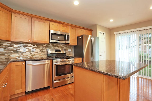 1437 Sturgeon Bay Ct, Schaumburg, IL 60173 - kitchen with appliances with stainless steel finishes, light wood finished floors, decorative backsplash, dark stone counters, and a kitchen island