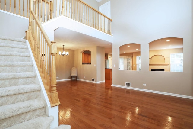 1437 Sturgeon Bay Ct, Schaumburg, IL 60173 - unfurnished living room with wood finished floors, arched walkways, a towering ceiling, and stairway
