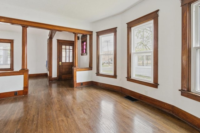 1006 W 1st St, Dixon, IL 61021 - unfurnished room featuring dark wood-type flooring, baseboards, and decorative columns