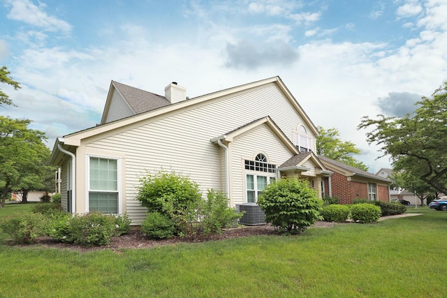 339 Ashford Cir Unit 1, Bartlett, IL 60103 - view of home's exterior with a chimney, a lawn, and central AC unit