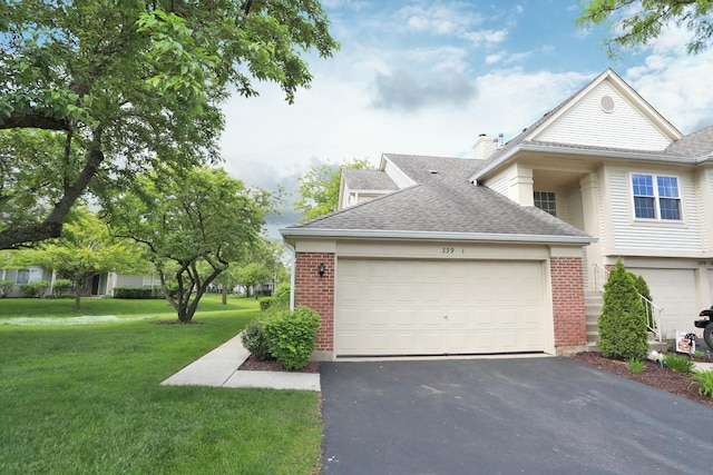 339 Ashford Cir Unit 1, Bartlett, IL 60103 - view of front facade with driveway, a shingled roof, a front lawn, brick siding, and a garage