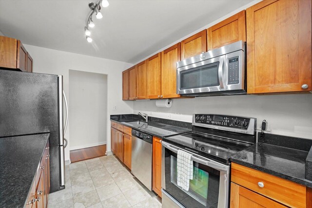 222 E Pearson St Unit 1504, Chicago, IL 60611 - kitchen featuring appliances with stainless steel finishes, a sink, brown cabinetry, dark stone countertops, and baseboards