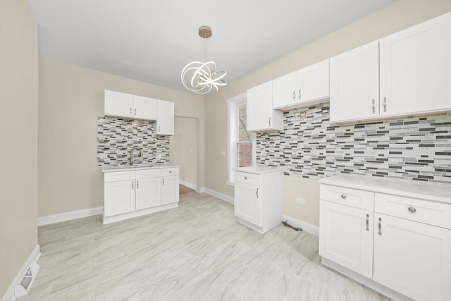 7421 S Eggleston Ave, Chicago, IL 60621 - kitchen featuring tasteful backsplash, a chandelier, light countertops, white cabinets, and a sink