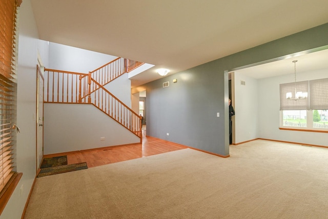 1804 Westbrook Ct, Plainfield, IL 60586 - unfurnished living room with carpet floors, a chandelier, stairs, baseboards, and wood finished floors