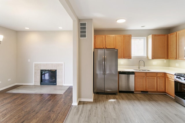 22429 Karlov Ave, Richton Park, IL 60471 - kitchen featuring stainless steel appliances, a sink, wood finished floors, light countertops, and a tiled fireplace