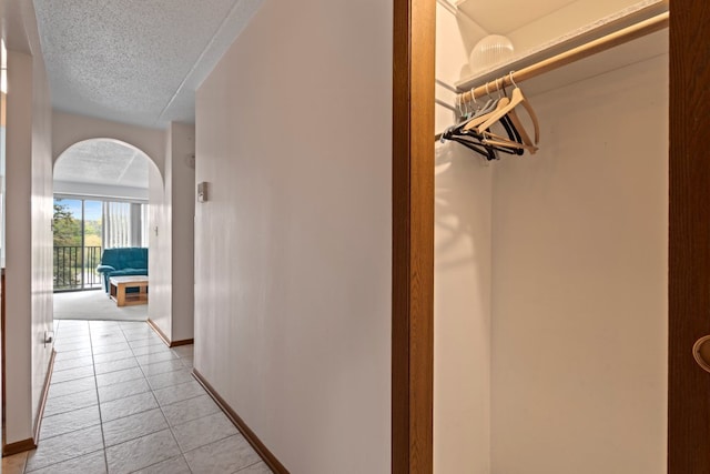 6950 W Forest Preserve Dr Unit 215, Norridge, IL 60706 - hallway with arched walkways, light tile patterned floors, a textured ceiling, and baseboards