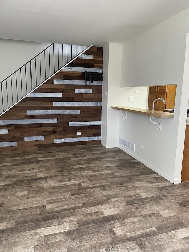 unfurnished living room with wood finished floors and stairway