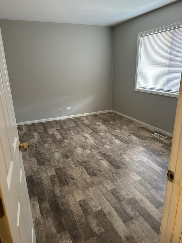 unfurnished room with dark wood finished floors and baseboards