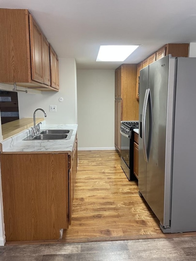 kitchen featuring stainless steel appliances, light wood finished floors, brown cabinets, and light countertops