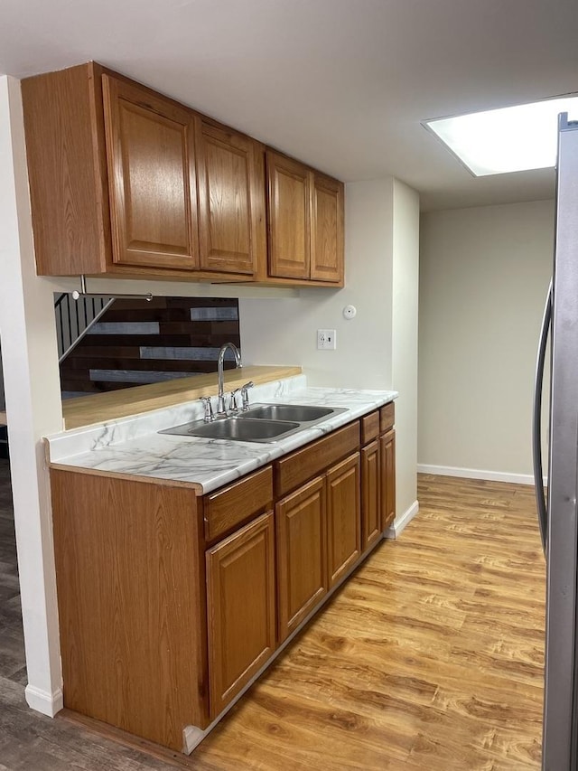 kitchen with freestanding refrigerator, light wood-style floors, light countertops, and brown cabinets