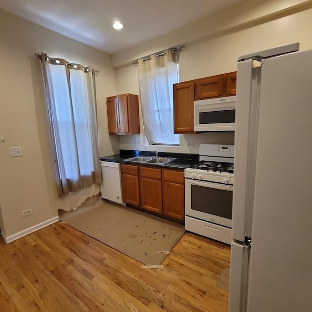 6033 S Prairie Ave, Chicago, IL 60637 - kitchen featuring white appliances, dark countertops, a sink, light wood-type flooring, and recessed lighting