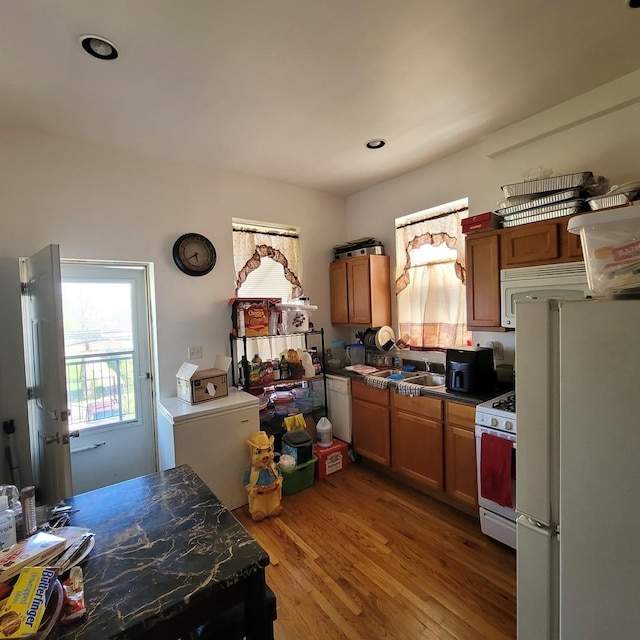 6033 S Prairie Ave, Chicago, IL 60637 - kitchen with white appliances, wood finished floors, brown cabinetry, dark countertops, and recessed lighting