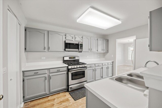 30W014 Willow Ln Unit 1, Warrenville, IL 60555 - kitchen featuring stainless steel appliances, a sink, gray cabinets, light wood-style flooring, and light countertops