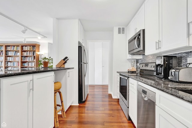 5455 N Sheridan Rd Unit 2206, Chicago, IL 60640 - kitchen featuring stainless steel appliances, decorative backsplash, white cabinets, wood finished floors, and dark stone counters
