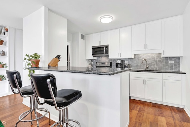 5455 N Sheridan Rd Unit 2206, Chicago, IL 60640 - kitchen with a sink, stainless steel appliances, a kitchen bar, and wood finished floors