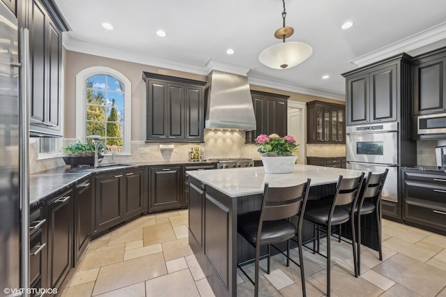 677 Greenleaf Ave, Glencoe, IL 60022 - kitchen featuring wall chimney range hood, a kitchen island, stainless steel appliances, a sink, and backsplash