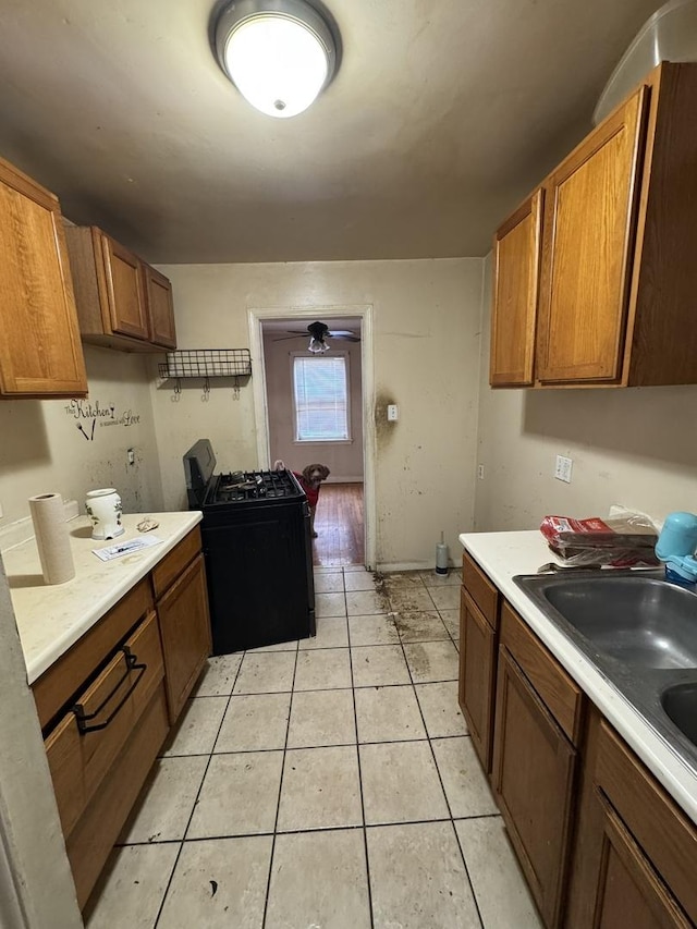 10035 S Yates Blvd, Chicago, IL 60617 - kitchen featuring gas stove, light countertops, brown cabinets, light tile patterned flooring, and a sink