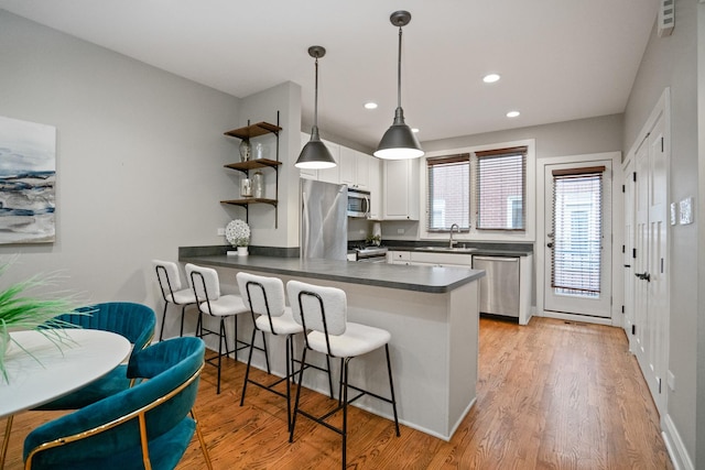 2803 N Wolcott Ave Unit D, Chicago, IL 60657 - kitchen with stainless steel appliances, dark countertops, a peninsula, open shelves, and a breakfast bar area