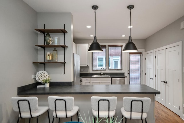 2803 N Wolcott Ave Unit D, Chicago, IL 60657 - kitchen with dark countertops, a sink, stainless steel appliances, a peninsula, and a breakfast bar