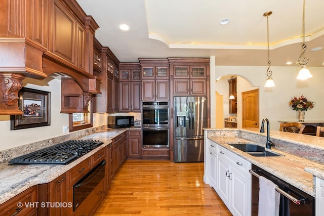 10944 Arbor Ridge Dr, Orland Park, IL 60467 - kitchen featuring appliances with stainless steel finishes, a warming drawer, arched walkways, light wood-style flooring, and white cabinetry