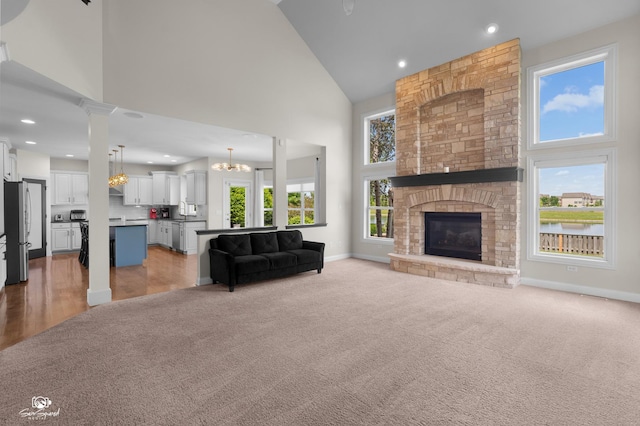 491 Bloomfield Cir W, Oswego, IL 60543 - living area featuring high vaulted ceiling, baseboards, light carpet, a fireplace, and a chandelier
