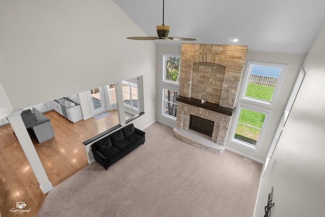491 Bloomfield Cir W, Oswego, IL 60543 - carpeted living room with a stone fireplace, ceiling fan, high vaulted ceiling, wood finished floors, and baseboards