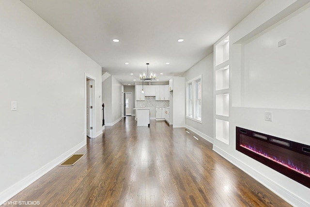7545 S Perry Ave, Chicago, IL 60620 - unfurnished living room featuring a chandelier, a glass covered fireplace, recessed lighting, dark wood-style floors, and baseboards