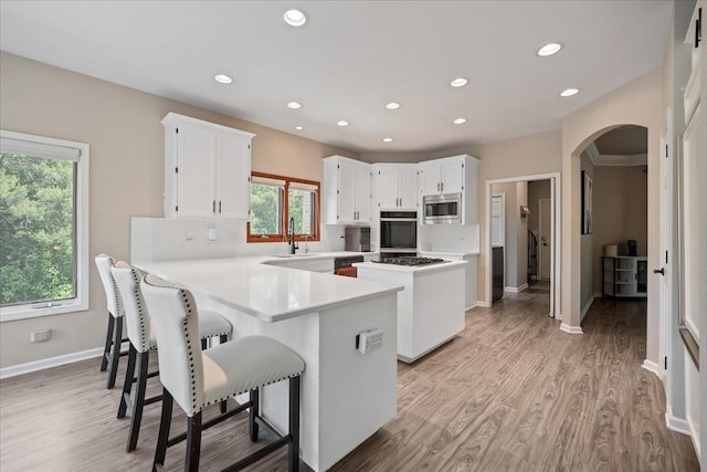 670 Leslie Ct, Carol Stream, IL 60188 - kitchen featuring stainless steel microwave, oven, arched walkways, a peninsula, and white cabinetry